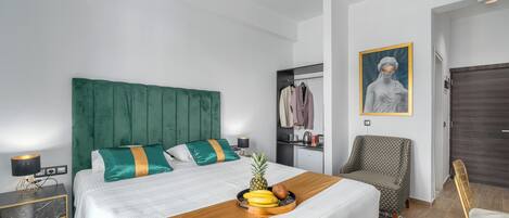 Una habitación de hotel ordenada con una cama grande, una mesita de noche, una silla y un escritorio pequeño con una lámpara.
