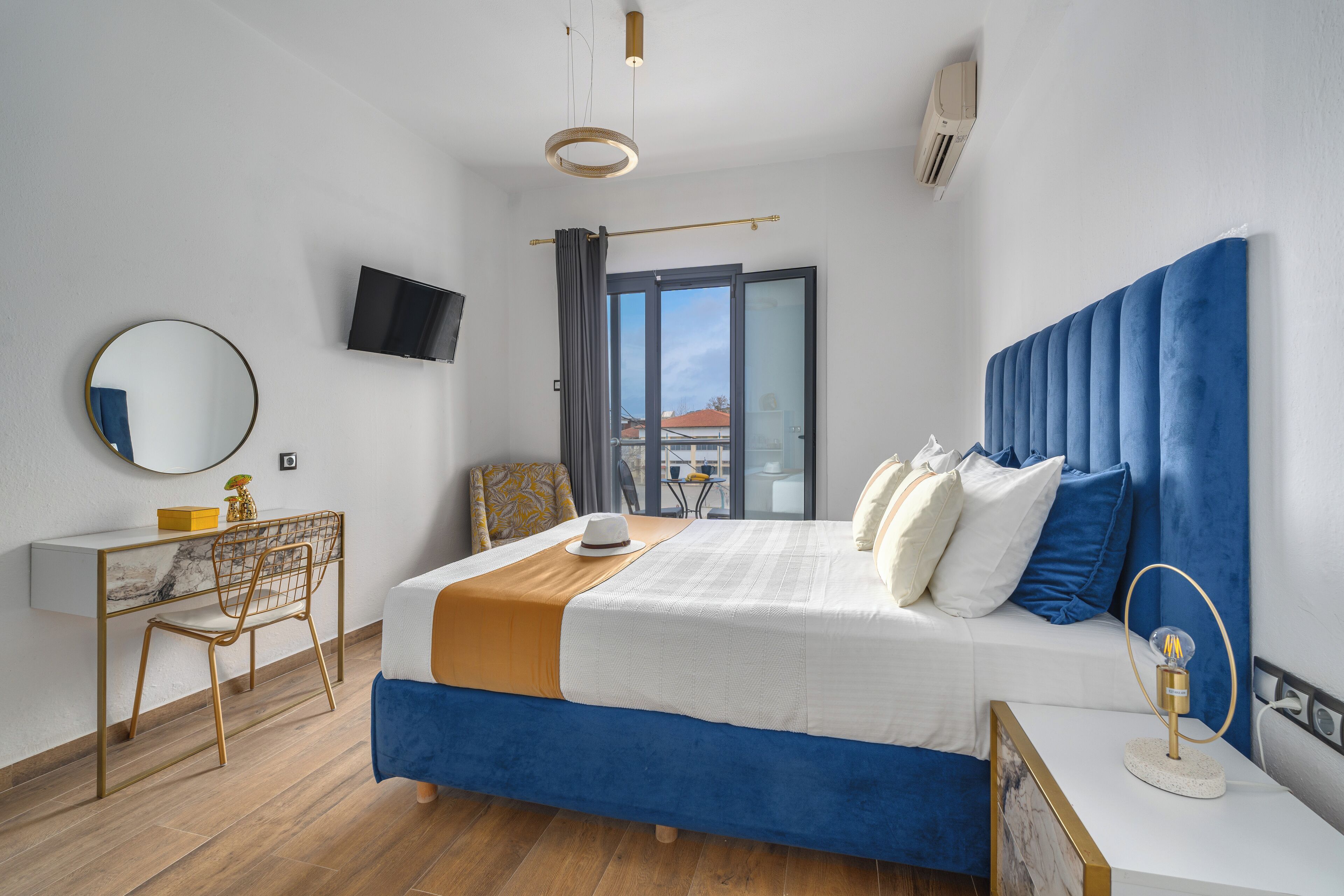 Habitación de hotel moderna con una cama grande, un escritorio con silla, televisión y vistas al exterior.