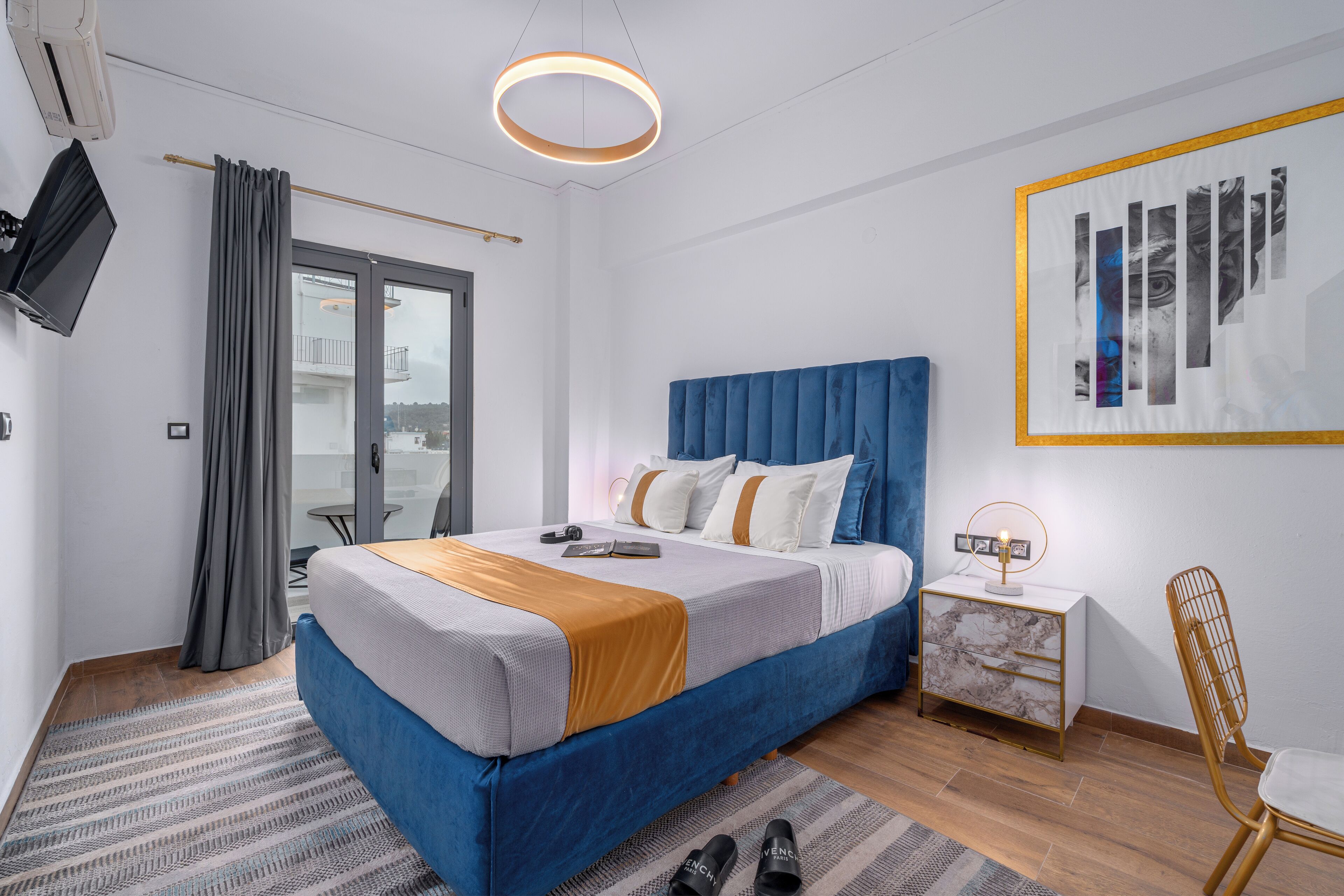 Ein zeitgemäßes Schlafzimmer mit einem Bett, einem Nachttisch, einem Sessel und einem Fernseher.