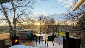 A cozy outdoor deck with a round table and chairs, a fire pit, and a view of the sunset. - Les Bulles Perchées de Lartigue (Margouet-Meymes)