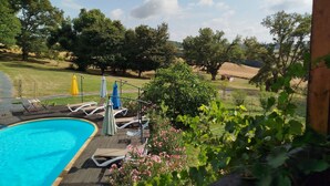 A pool area with lounge chairs and umbrellas, surrounded by greenery and trees. - Les Bulles Perchées de Lartigue (Margouet-Meymes)