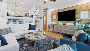 A modern living room with a sofa, coffee table, and a flat-screen TV mounted on the wall. - 95100 Sandpiper - Beautiful Oceanfront 2 BR Condo on Amelia Island (Fernandina Beach)