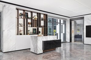 Un área de recepción moderna con un mostrador de mármol, separadores de vidrio y diversos objetos decorativos.