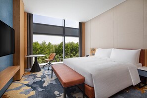 Una habitación de hotel moderna con una cama grande, un escritorio, una silla y un televisor.