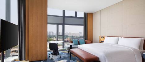Una habitación de hotel con una cama grande, un escritorio, una silla y un televisor.