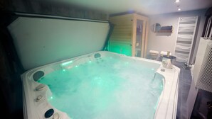 A hot tub with a green light, a wooden cabinet, and a towel rack. - LE COLVERT 4-star furnished holiday home with PRIVATE JACUZZI and PRIVATE SAUNA (Le Hanouard)