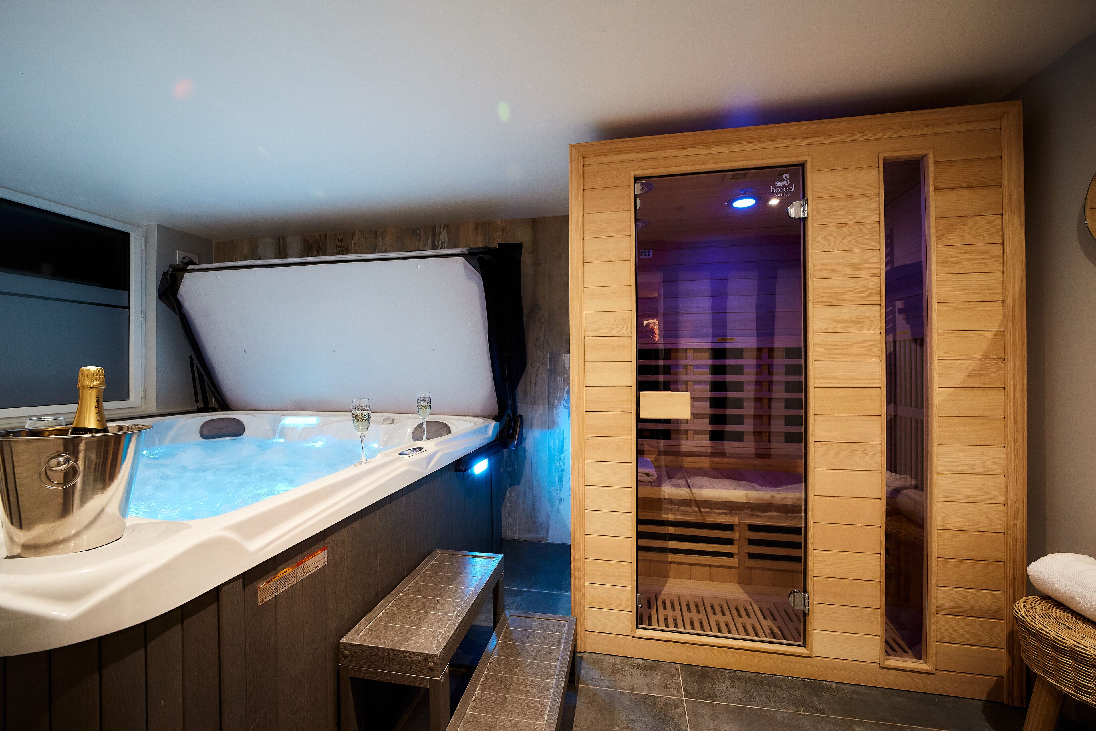 A spa room with a wooden sauna, a hot tub, and a bench.