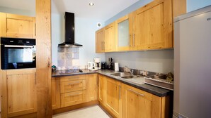 A modern kitchen with wooden cabinets, a stainless steel sink, and a built-in oven. - LE COLVERT 4-star furnished holiday home with PRIVATE JACUZZI and PRIVATE SAUNA (Le Hanouard)