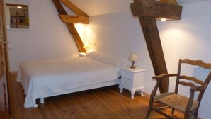 Un dormitorio con techo de madera, una cama, una mesita de noche con lámpara y una silla.
