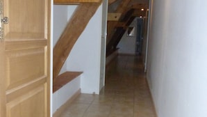 Un estrecho pasillo con vigas de madera y suelo de baldosas.