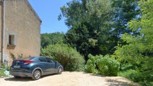 Un coche azul aparcado en un camino de grava junto a un edificio con una ventana y una puerta.