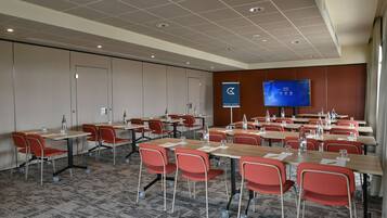 A conference room with tables, chairs, a television screen, and a door.