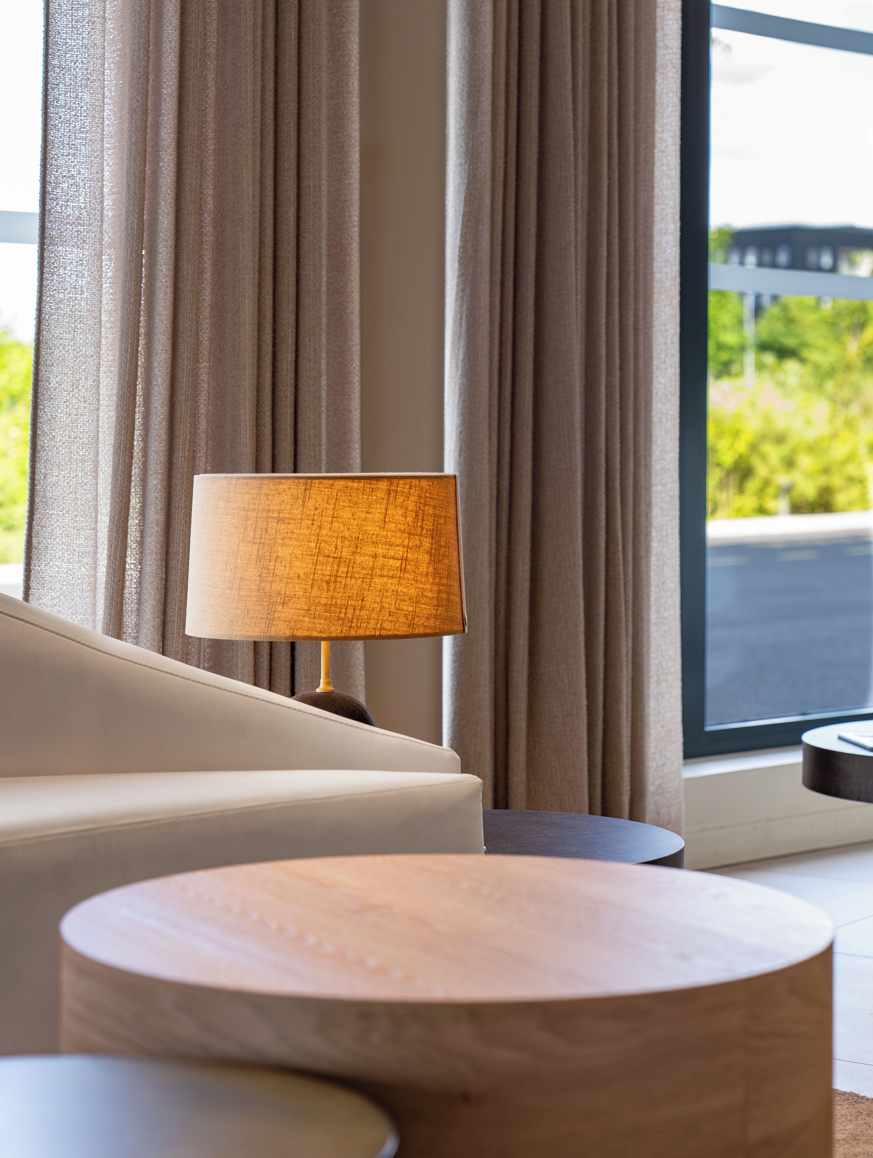 A modern living room with a sofa, a round wooden coffee table, and a lamp.