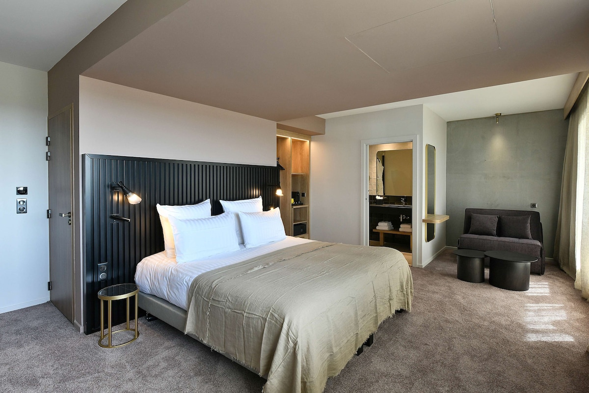 Une chambre moderne avec un grand lit, des tables de chevet, un canapé et une armoire intégrée.