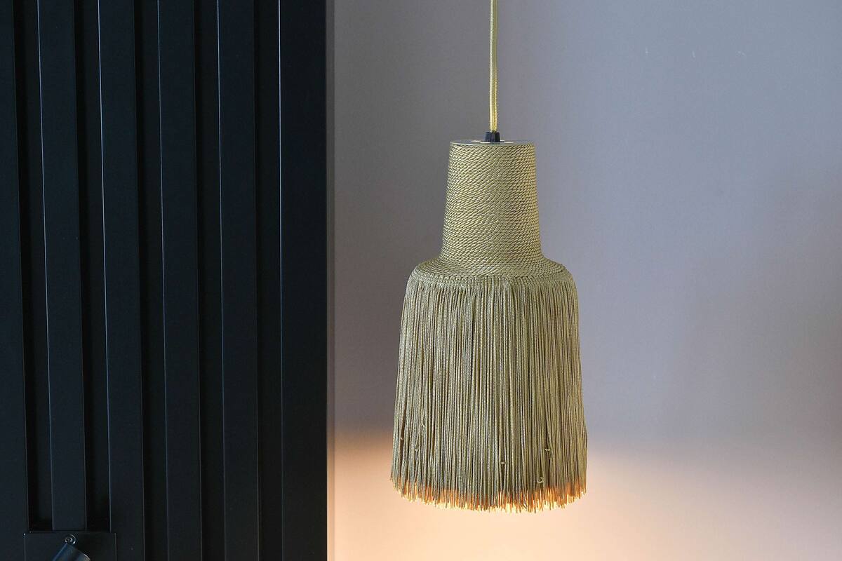 Un luminaire suspendu, de type suspension, doté d’un abat-jour texturé et orné de franges.