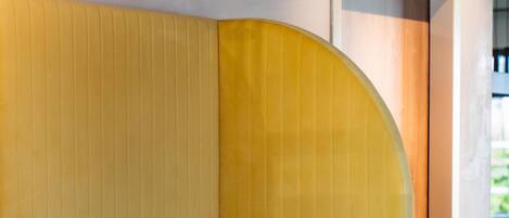 A yellow upholstered booth with a curved backrest and a dark-colored table.