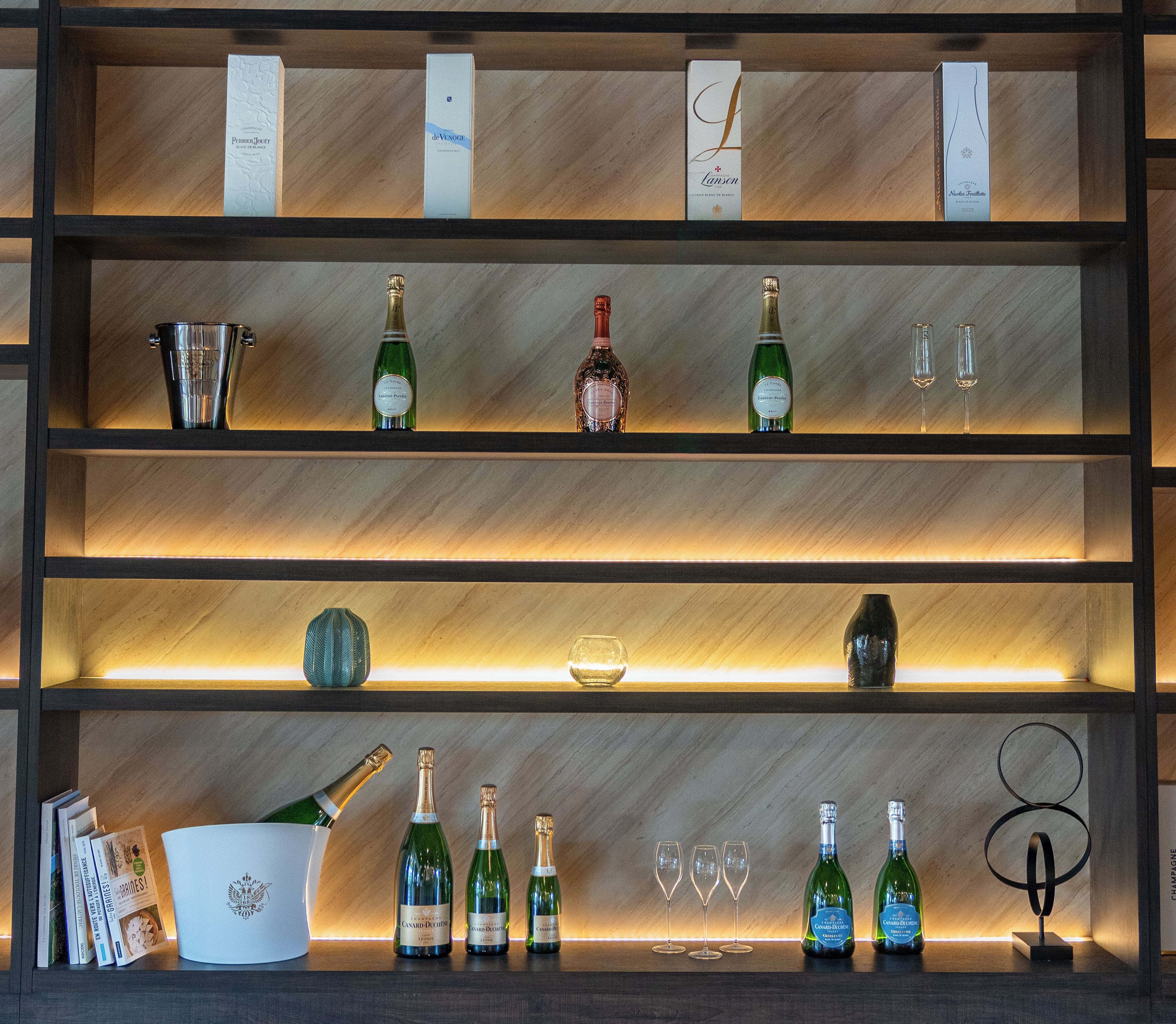 A wine display with bottles and glasses on shelves.