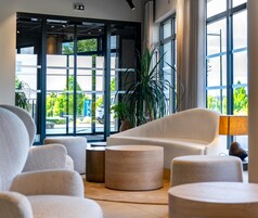 A modern lobby with a seating area, large windows, and a plant.