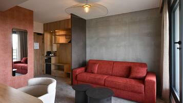 A modern living room with a red sofa, a round table, and a unique ceiling light fixture.