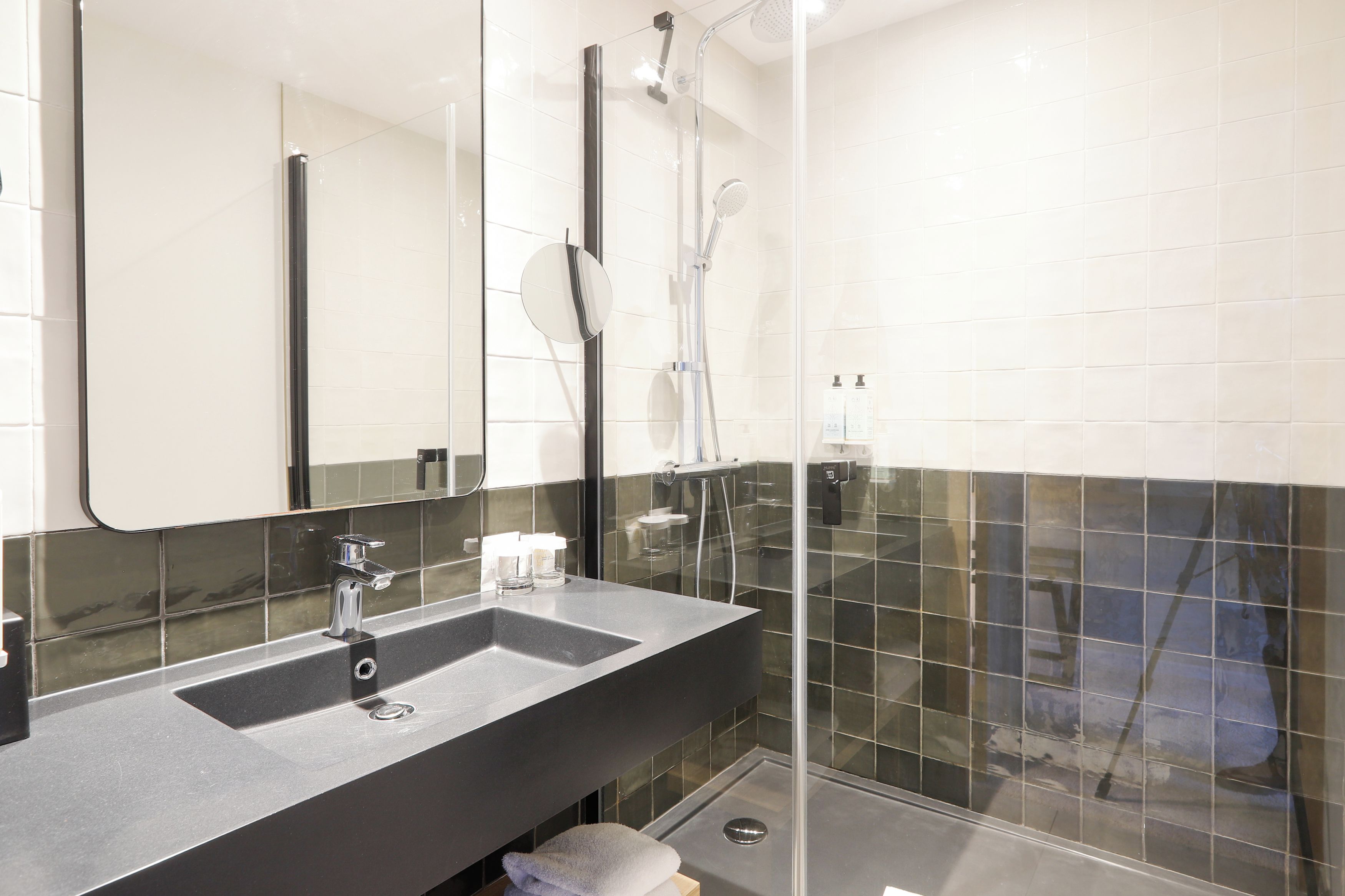 Een moderne badkamer met een grote spiegel, een wastafel en een douchecabine.