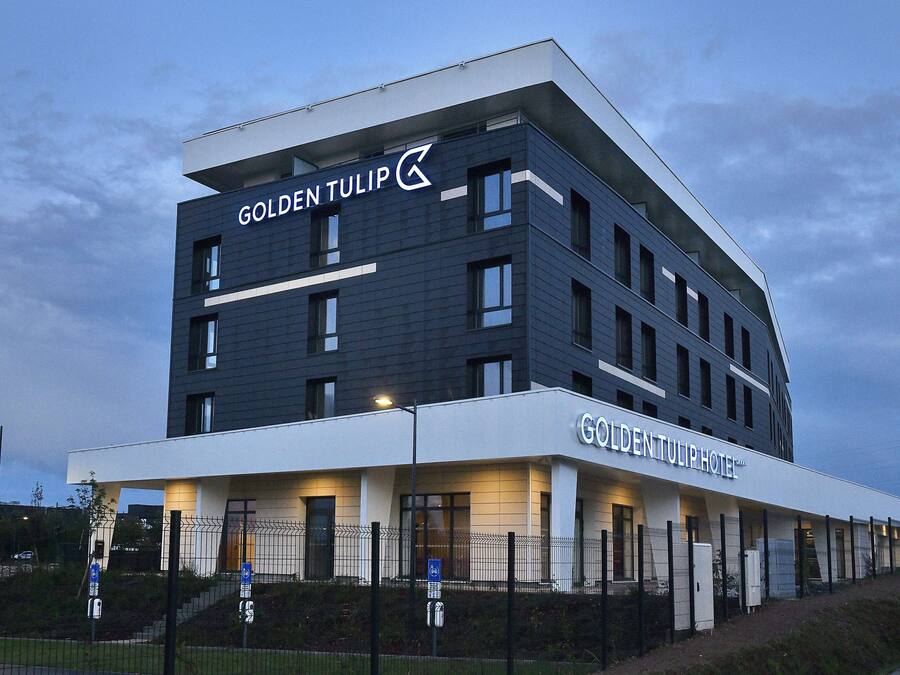 A modern hotel building with a prominent sign reading "Golden Tulip Hotel".