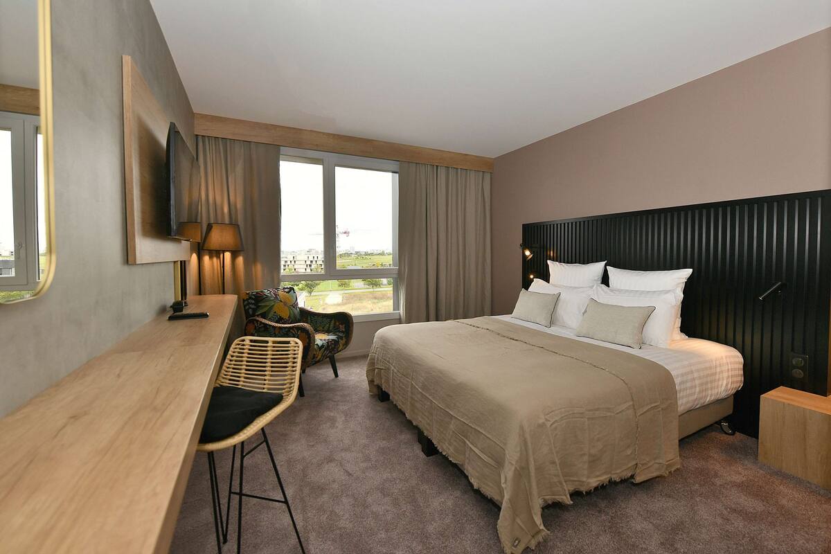 Une chambre d’hôtel moderne avec un grand lit, un bureau et une chaise.