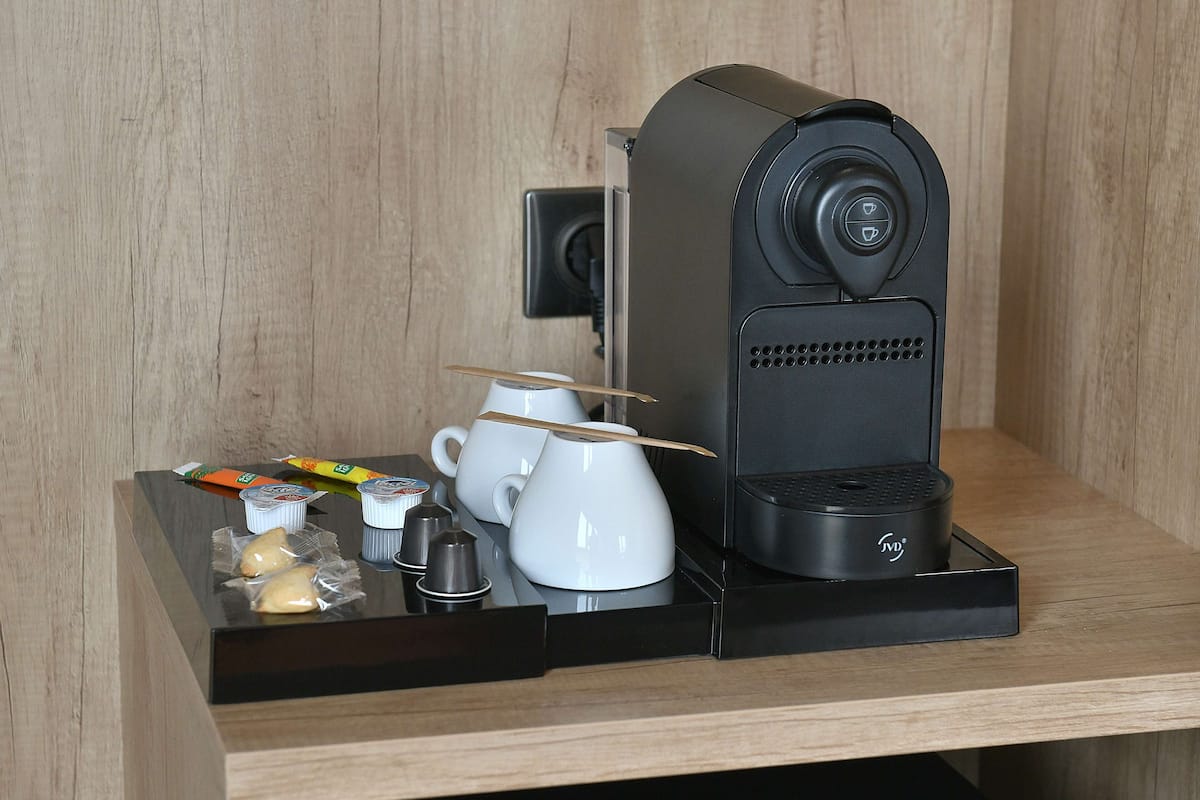 Un ensemble compact pour préparer le café, comprenant une machine à café, des tasses et des condiments.