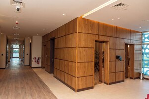 Un pasillo con paneles de madera, un extintor y vistas al exterior.