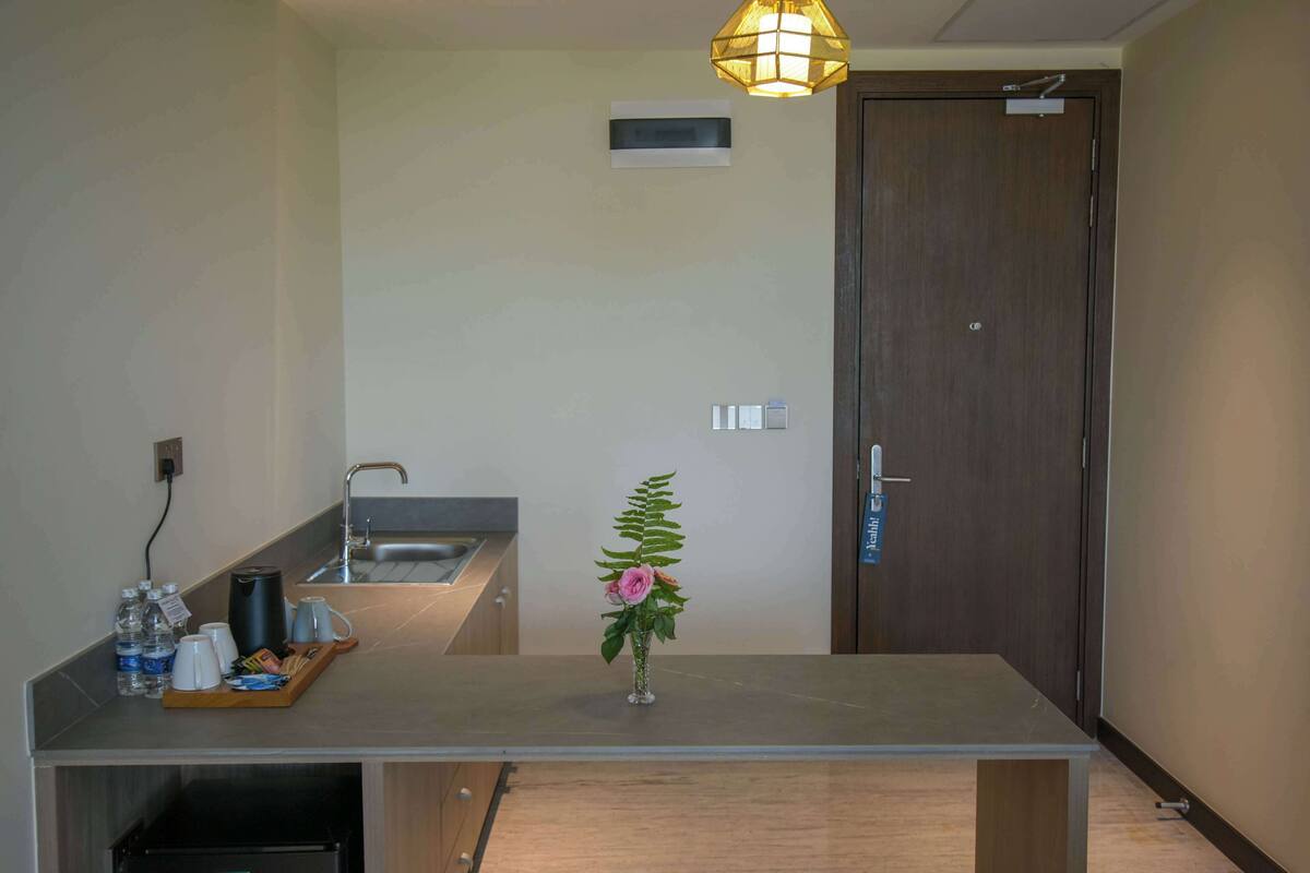 A modern kitchen with a countertop, a sink, a coffee maker, and a vase with a flower.