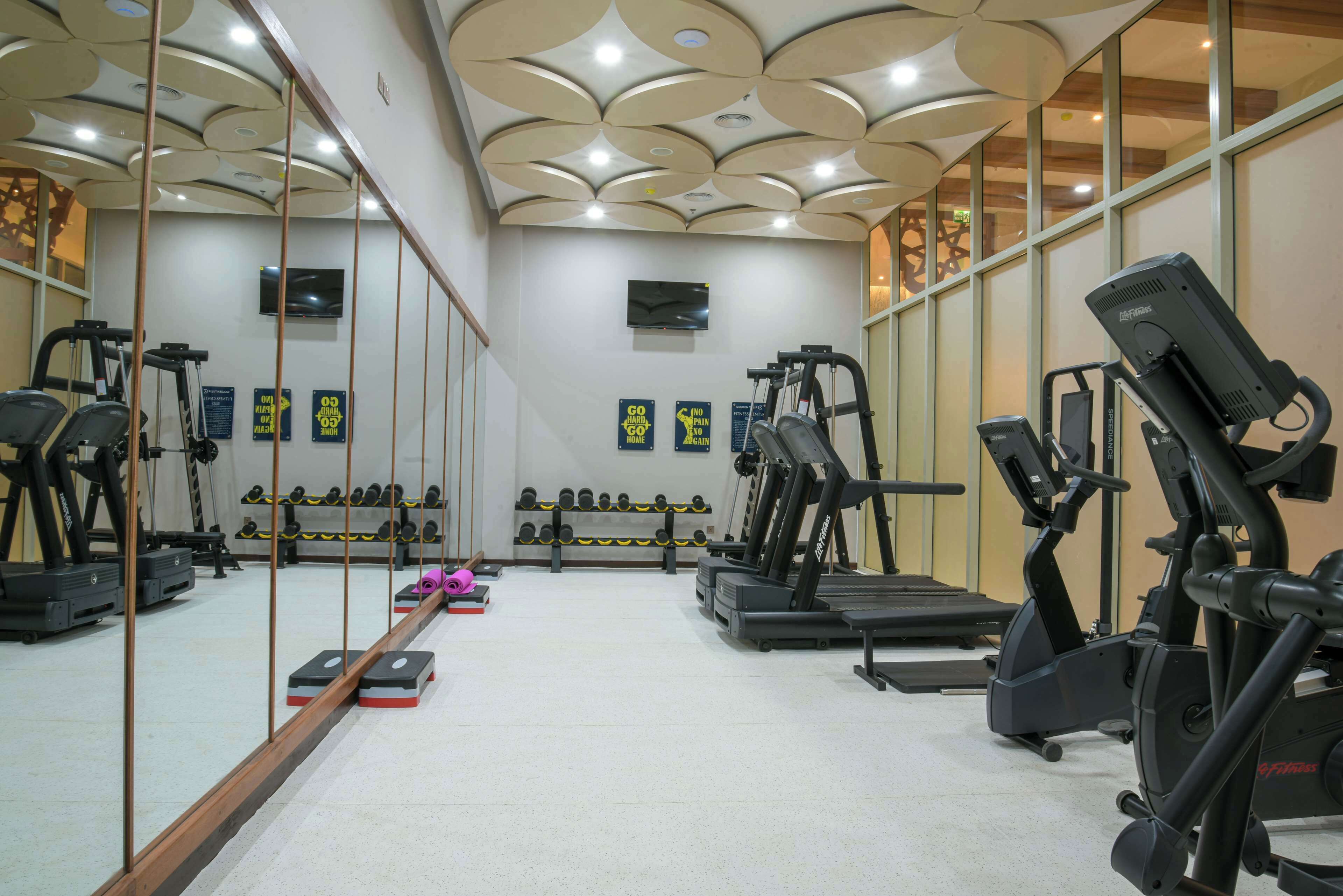 A gym with exercise equipment, mirrors, and motivational posters.