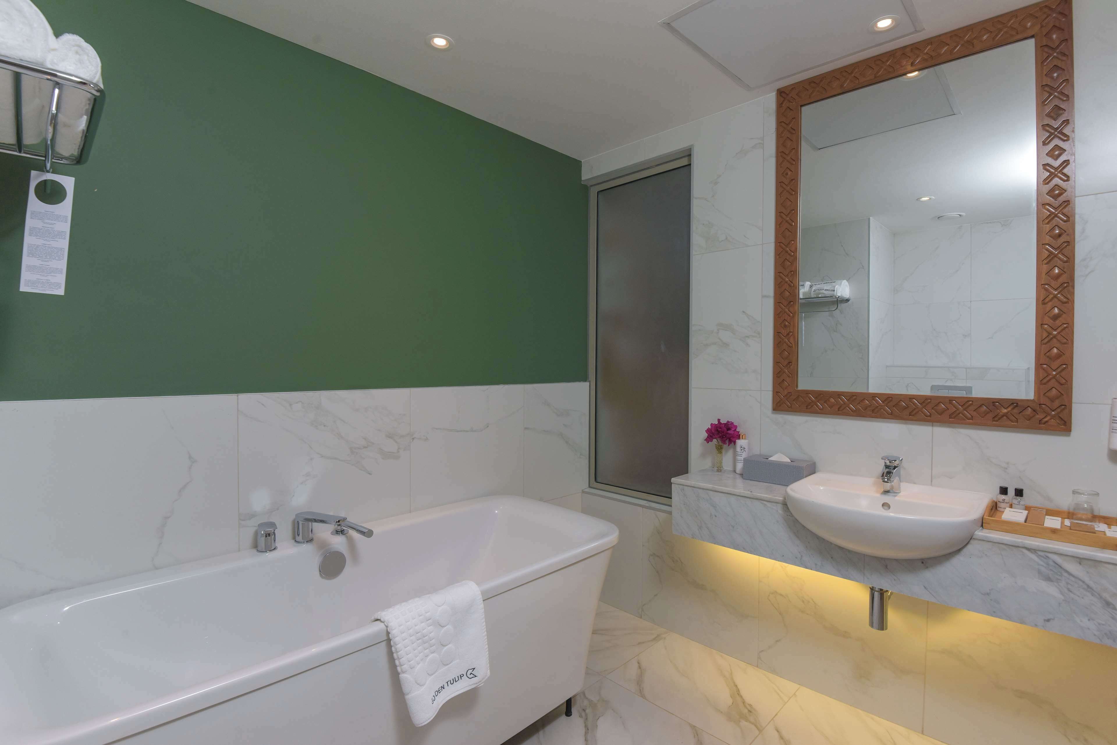A modern bathroom with a bathtub, a sink, and a large mirror.