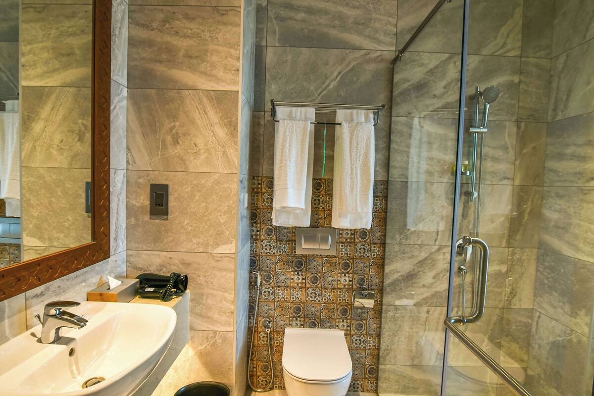 A bathroom with a marble sink, a toilet, and a glass-enclosed shower.