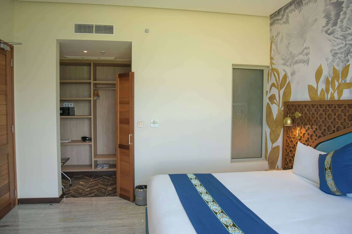 A hotel room with a bed, a wardrobe, a small kitchenette, and a decorative wall.