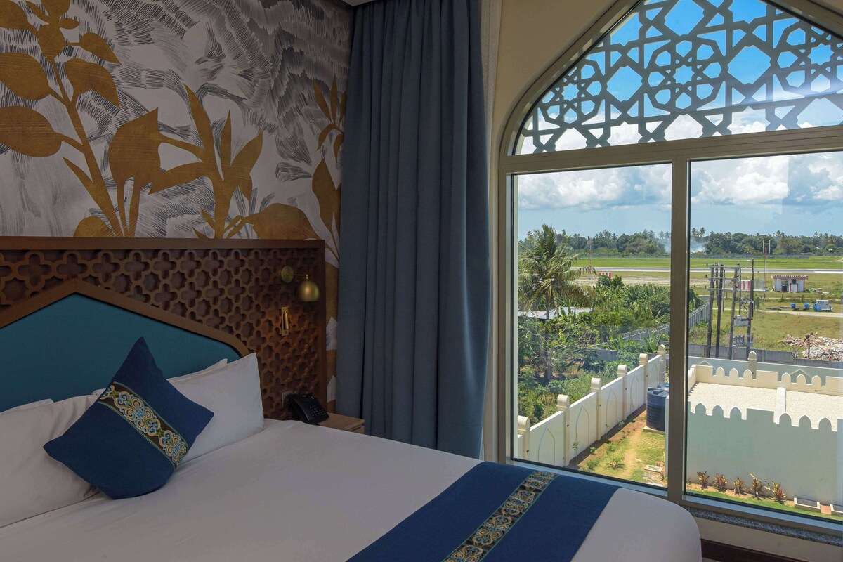 A hotel room with a large bed, a view of a golf course, and a decorative wall.
