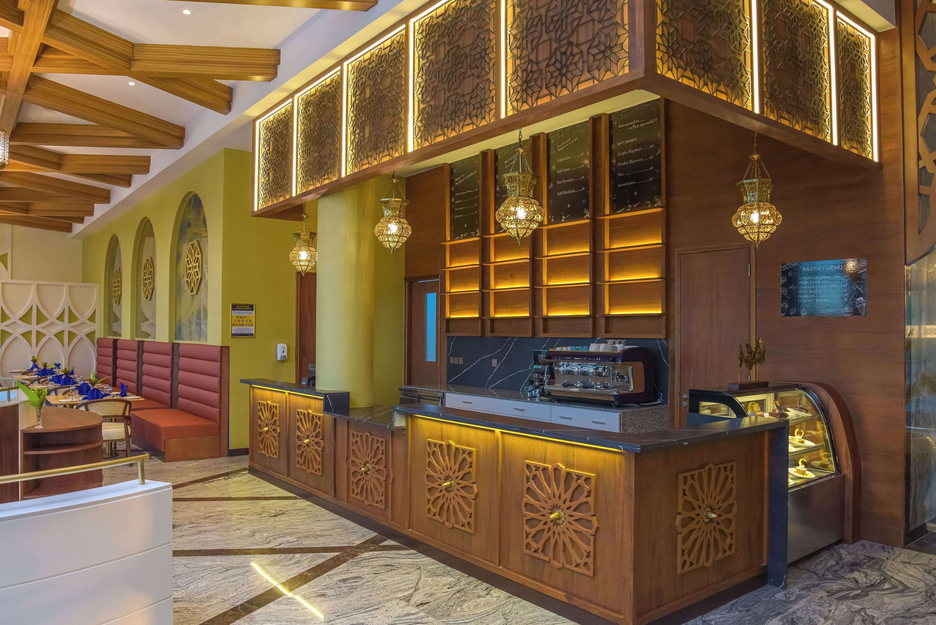 A hotel lobby with a reception desk, seating area, and decorative wall panels.