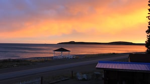 A coastal road with a gazebo, a small building with a blue roof, and a view of the sea at sunset. - Bunky on the Beach · UNESCO Geopark (Saint Martins Parish)
