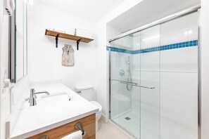A modern bathroom with a glass shower enclosure, a white sink, and a wooden vanity. - Vermont get-away end unit townhouse nestled in the trees (Hartford)
