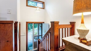 A staircase with wooden railings and a view of a forest through a glass door. - Vermont get-away end unit townhouse nestled in the trees  (Hartford)