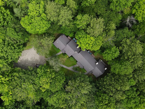 An aerial view of a building surrounded by dense green forest. - Vermont get-away end unit townhouse nestled in the trees (Hartford)
