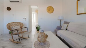 A modern living room with a sofa, a rocking chair, a coffee table, and decorative items. - Le Pitchoun - One Bedroom Apartment, Sleeps 2 (Marseille)