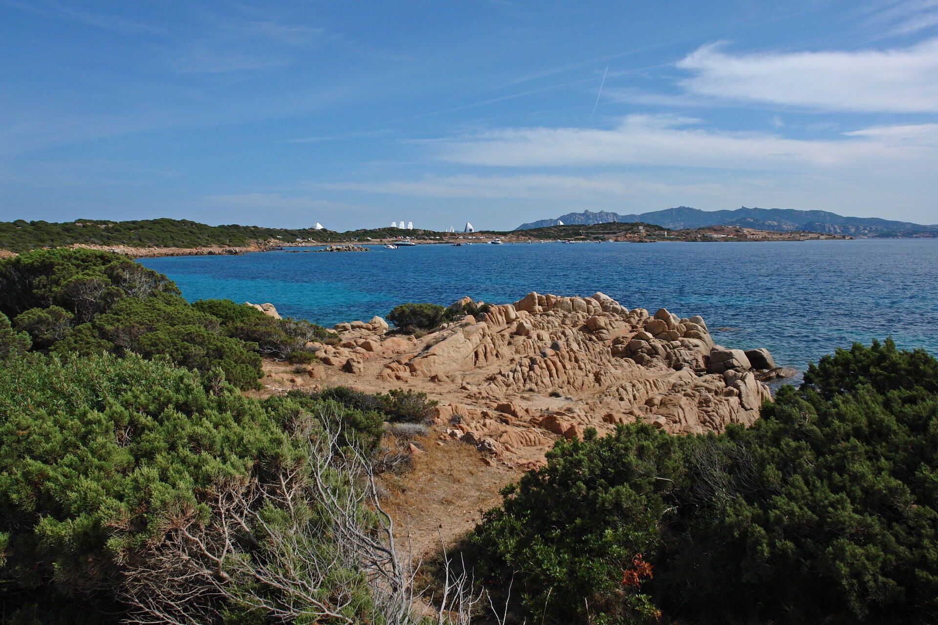 A coastal landscape with rocky terrain and dense greenery.