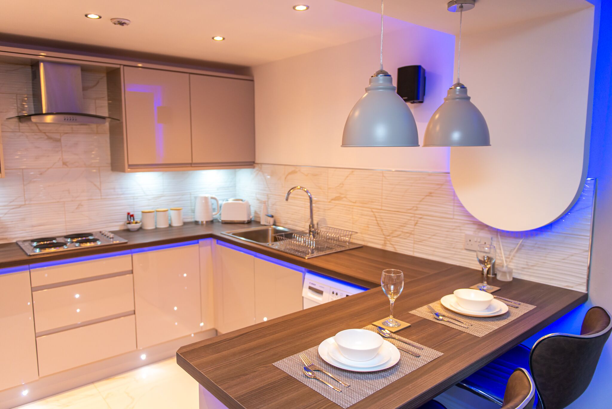 A modern kitchen with a central island, built-in appliances, and pendant lighting.