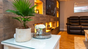 A reception area with a potted plant, a tray with a vase and flowers, and a seating area with leather chairs.