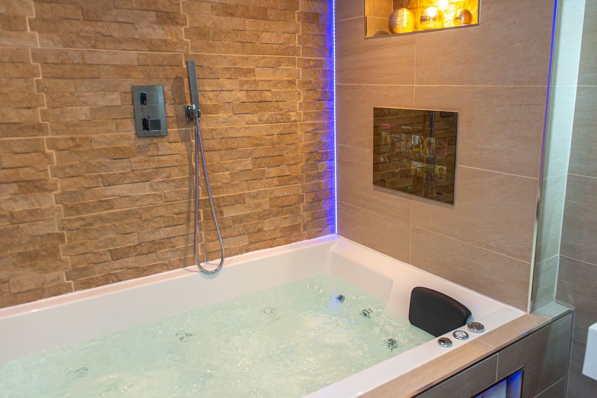 A modern bathroom with a stone wall, a bathtub, and a shower area.