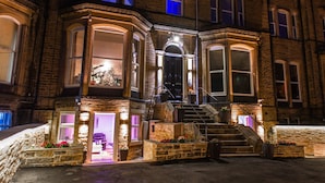 A historic building with a grand entrance, stone steps, and a well-lit interior.