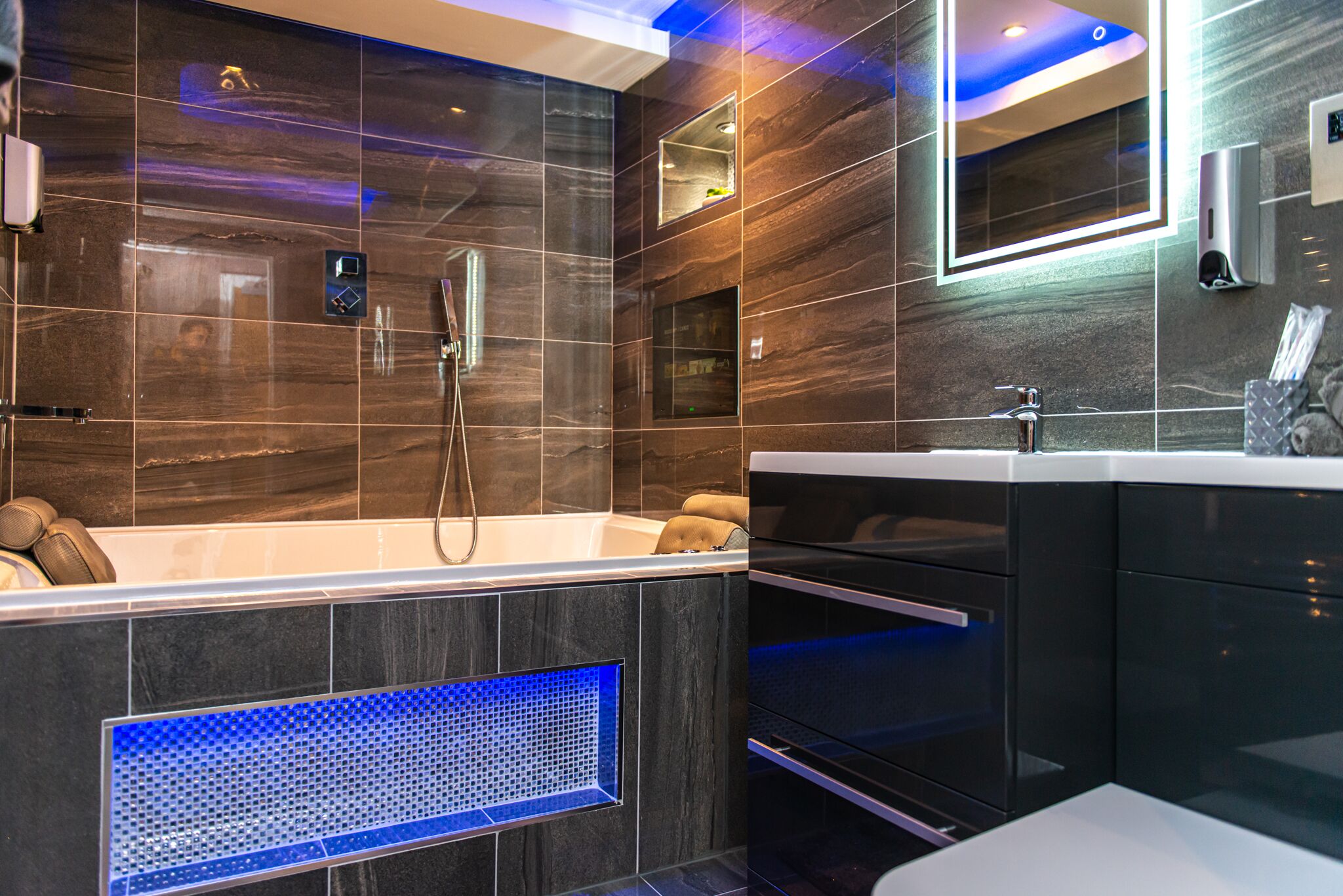 A modern bathroom with a large bathtub, a mirror, and a built-in heater.
