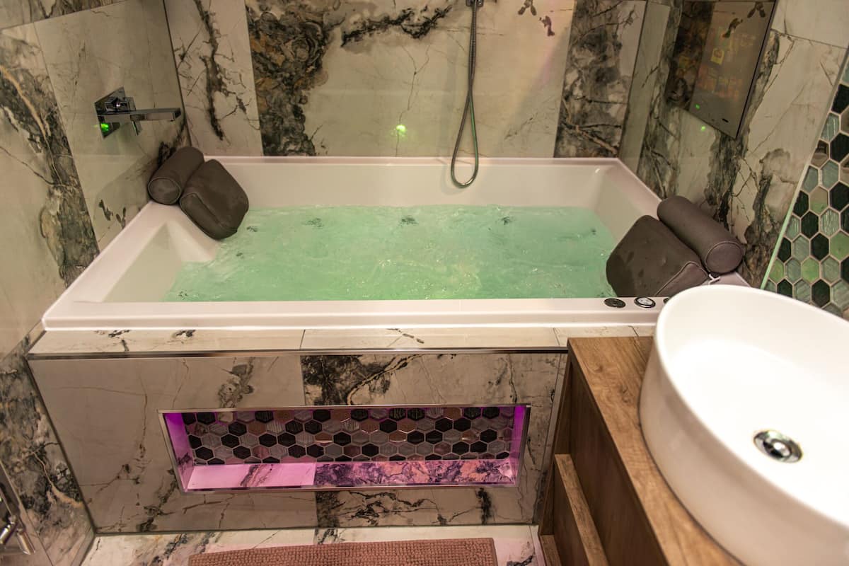 A modern bathroom with a rectangular bathtub, a wooden vanity, and a white sink.