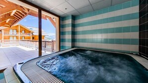 Un bain à remous avec vue sur un bâtiment en bois, un balcon et des murs à rayures.
