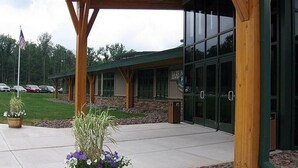 A building with a covered entrance, large windows, and a stone facade.