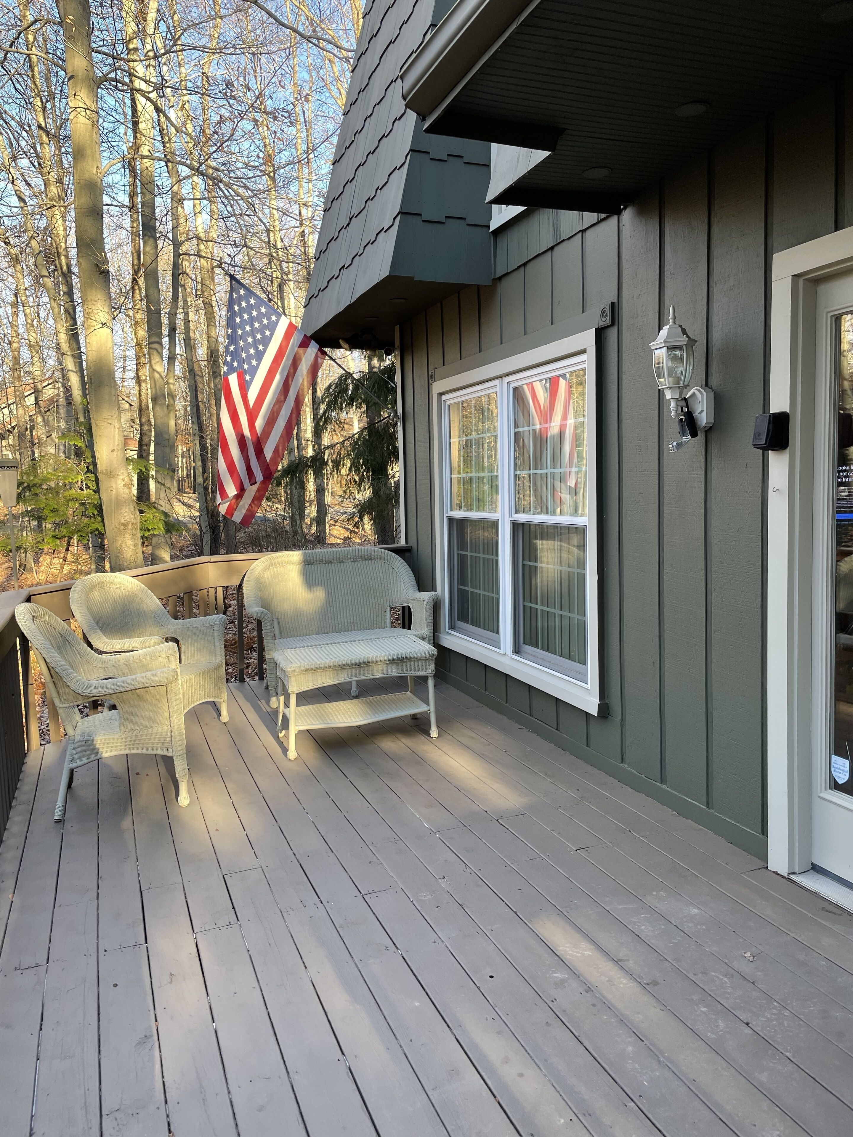 A wooden deck with wicker furniture and an American flag.
